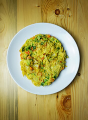 The omelette using onions is placed on a white plate with a wooden base visible from above