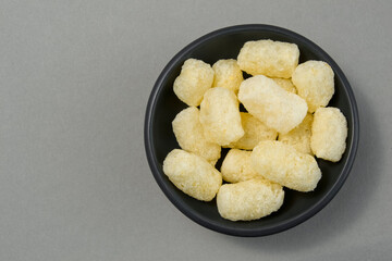 corn sticks in a black bowl on a gray background. a bunch of sweets. air sticks