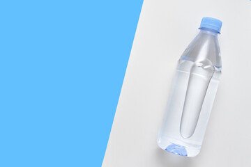Plastic bottle with water on a white and blue background with copy space