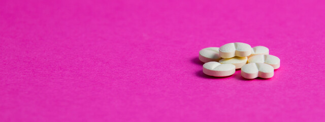 Pills on pink paper background with copy space. Covid 19 treatment concept, banner format