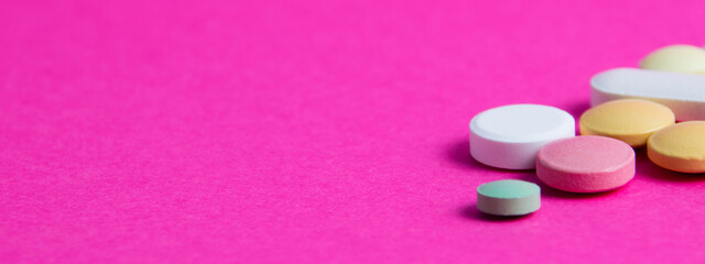 Pills on pink paper background with copy space. Covid 19 treatment concept, banner format