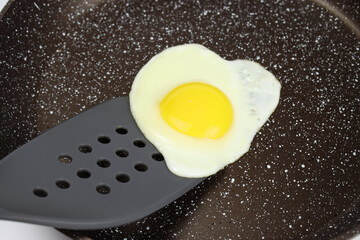 A spatula lifts the scrambled eggs in a non-stick frying pan