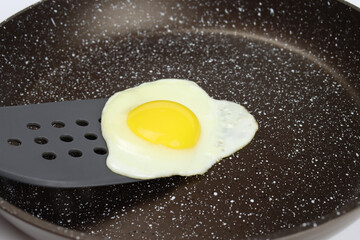 A spatula lifts the scrambled eggs in a non-stick frying pan