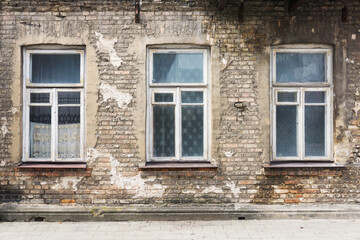 Fototapeta na wymiar Old ruined building window. Brick wall apartment building background. Post war architecture. Broken old wooden window frame. Historic tenement house background.