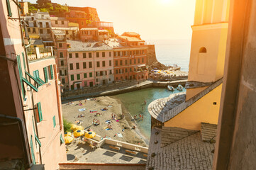 Vernazza, Liguria, Italy. June 2020. A point of view between the houses overlooking the beach of the village. People bathe in the waters of the marina. Famous tourist destination.