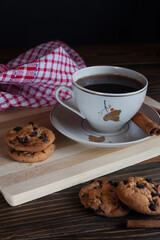 A cup of aromatic black coffee on a wooden table. Morning espresso or Americano coffee for breakfast in a beautiful cup. Still life. Cinnamon sticks. 