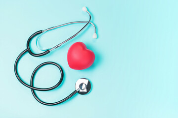Stethoscope and red heart on a blue background top view, copy space.