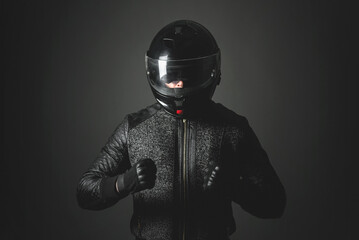 Aggressive motorbiker is showing his fists on the dark background.