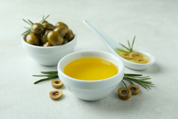 Bowls with olives and oil on white textured background