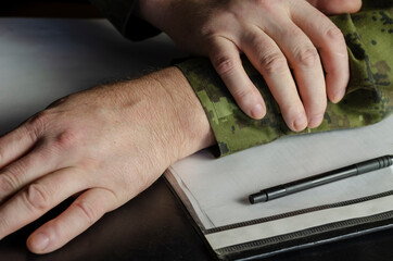 Officer's hands, document folder on black desk in close-up.