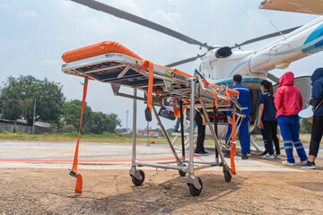 A stretcher is parked in front of a helicopter to transport a sick person.
