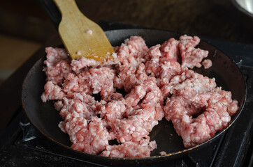 A man is frying minced meat in a pan.