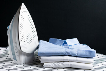 Electric iron and shirt on the ironing board in the room