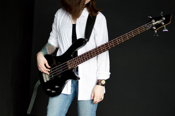 a girl guitarist stands with an electric guitar on a dark background.