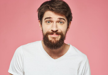 Fototapeta premium Portrait of a happy man with a beard on a pink background in a white T-shirt