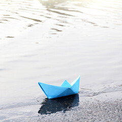 blue paper boat on the shore of the reservoir. waiting for a tailwind
