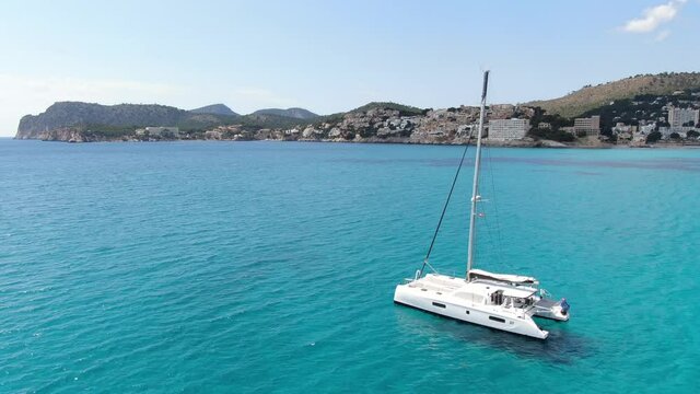 Catamaran on the beach in mallorca with beaturiful view of the sea with crystalclear water. Sea view of turquoise colour. Concept of summer, travel, relax and enjoy
