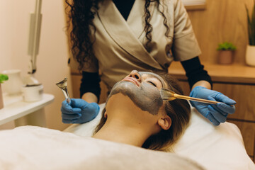 Applying facial mask at woman face at beauty salon