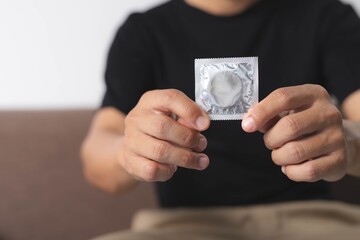 A man is hold a condom envelope to prevent contraception or sexually transmitted diseases.,World aids day.Safe sex concept.