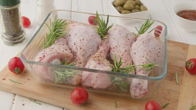 Chef marinates raw chicken legs with sauce.Salt on raw chicken legs.
Cooking chicken legs with spices, garlic and rosemary. Cooking food concept.