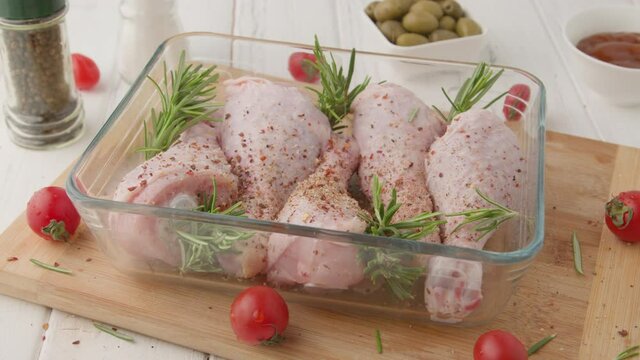 Chef marinates raw chicken legs with sauce.Salt on raw chicken legs.
Cooking chicken legs with spices, garlic and rosemary. Cooking food concept.