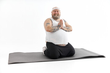 Sporty fat man with beard and tattoos is doing yoga