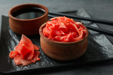 Plate with pickled ginger, soy sauce and chopsticks on dark wooden background