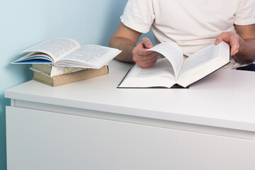 Male hand holding open book in library. Reading club meeting concept. Student studying at home