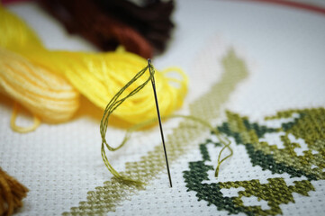 cross-stitch with colored threads on a white canvas hobby craft 