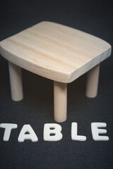 wooden table with lettering on black background furniture toy doll house model natural material decor design vertical image postcard 