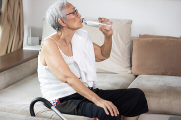 Thirsty senior woman suffering from heat,drinking fresh water from a bottle to quench their thirst in hot summer weather,high temperature on a sunny day,feeling thirsty,water balance,lifestyle concept - obrazy, fototapety, plakaty