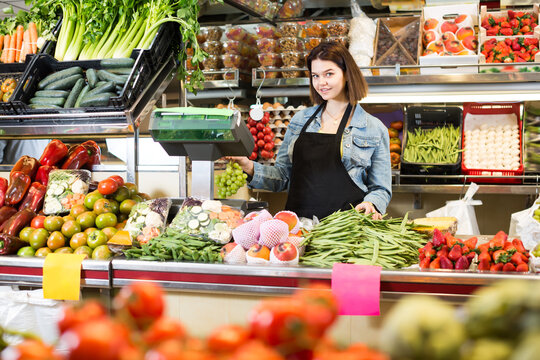 Happy woman seller displaying assortment of grocery shop