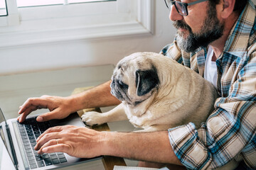 Portrait of man and dog working together at home with laptop computer - concept of free smart work lifestyle people - caucasian typing on keyboard at workstation - modern online job business digital