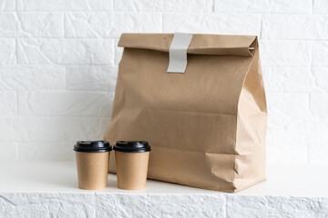 Fast food packaging set. Paper coffee cups in holder, food box, brown paper bag on the table