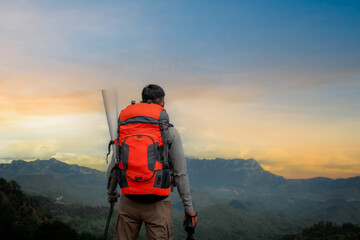 Young man with a backpack enjoying the sunset on the top of the mountain Travel traveler on valley...