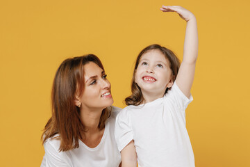 Woman in white t-shirt with child baby girl 5-6 years old hold hand above head show how much she...