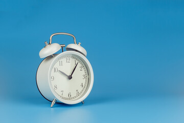 White alarm clock on blue background.