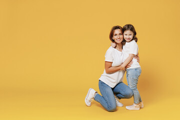 Full length happy woman in basic white t-shirt have fun with cute child baby girl 5-6 years old hold hands. Mom little kid daughter isolated on yellow color background studio Mother's Day love family