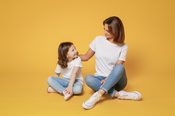 Fototapeta na wymiar Full body length happy woman in basic white t-shirt have fun sit on floor with child baby girl 5-6 year old Mom little kid daughter isolated on yellow color background studio Mother's Day love family
