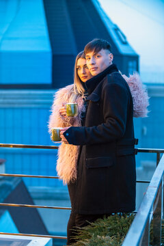 couple with mugs on the terrace of a high-rise building