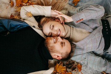 a couple in love is sitting on the ground with autumn leaves