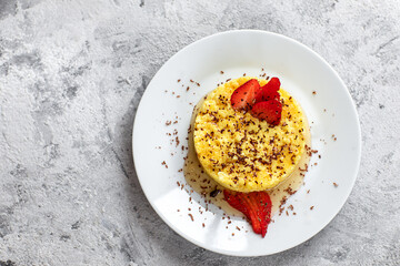 Millet porridge with strawberries, honey and chocolate on a gray background