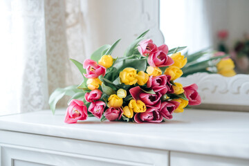 Fresh spring yellow and pink tulips bouquet on white wood table background in mirror with copy space for text. Love, easter, International Women, Mother and Happy Valentine day concept