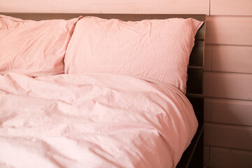 Interior of bedroom in light pink tones. Pillows and blanket with natural cotton in pink tone