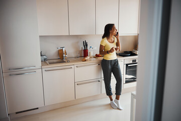 Cheerful young woman talking on mobile phone at home