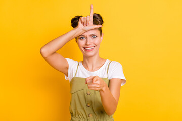 Photo of crazy tricky lady evil smile show horn direct finger camera wear green overall isolated yellow background