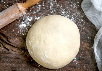Raw dough for bread or pizza on a dark background