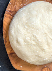 Risen yeast dough for bread or pizza on a floured surface
