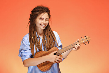 Portrait of funny young woman playing ukulele. Happiness and carefree concept