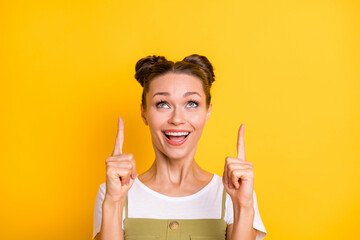 Portrait of attractive cheerful girl demonstrating up copy space offer ad solution isolated over bright yellow color background